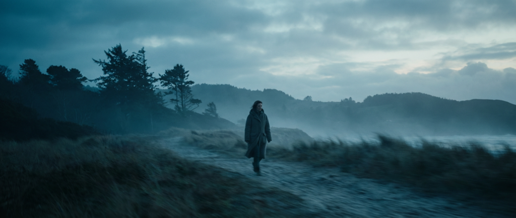 woman walking outdoors in a cold, misty landscape, contemplating transition anxiety therapy.