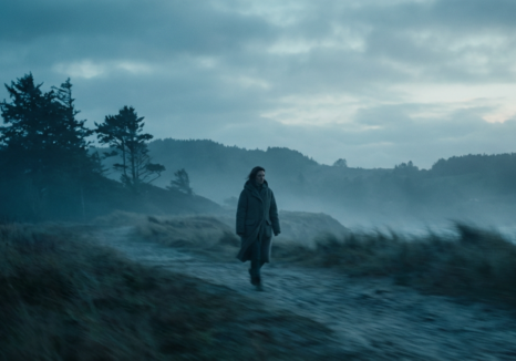 woman walking outdoors in a cold, misty landscape, contemplating transition anxiety therapy.