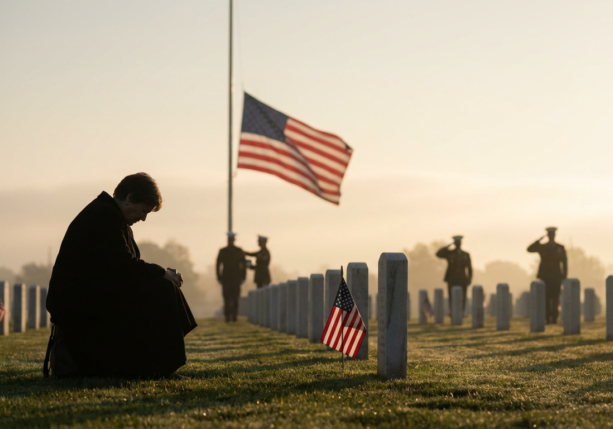 kneeling person grieving in a military graveyard with flags at sunrise, for memorial day grief counseling