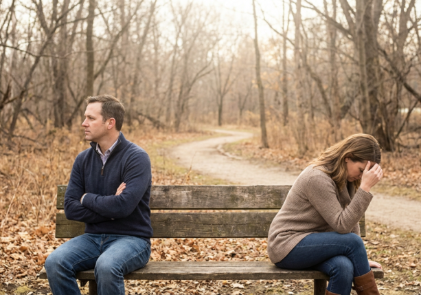 upset couple on a park bench, backs turned from each other, indicating relationship tensions.