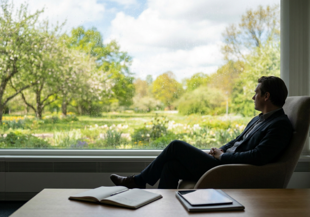 man gazing out a window at a spring garden during may weather depression.